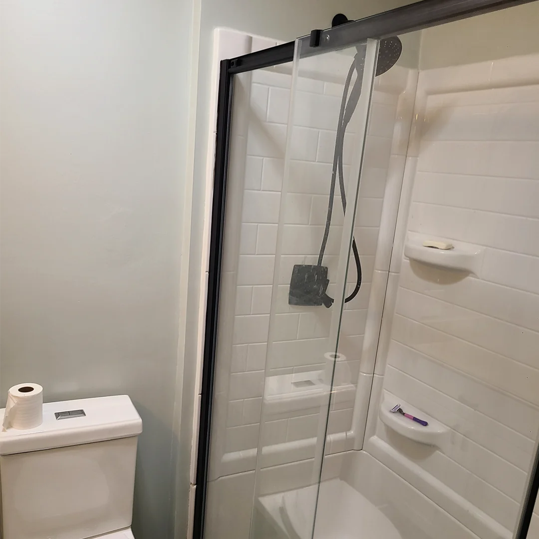 Shower with white wall surround and sliding glass door