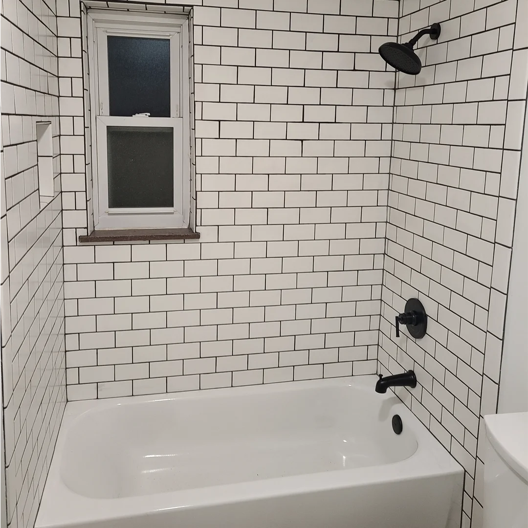 Bathtub with white subway tile surround and matte black fixtures