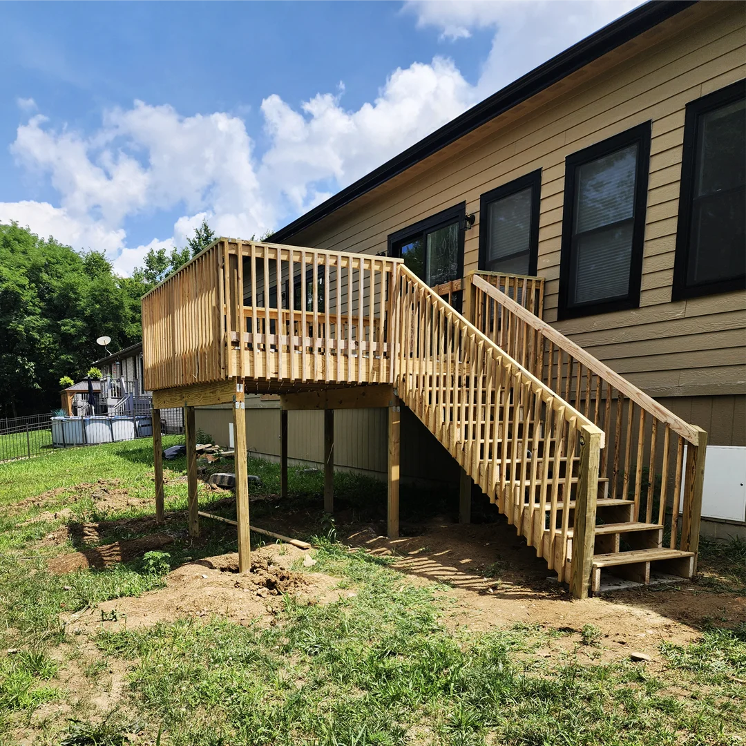Raised pressure-treated deck with staircase on the side of a home