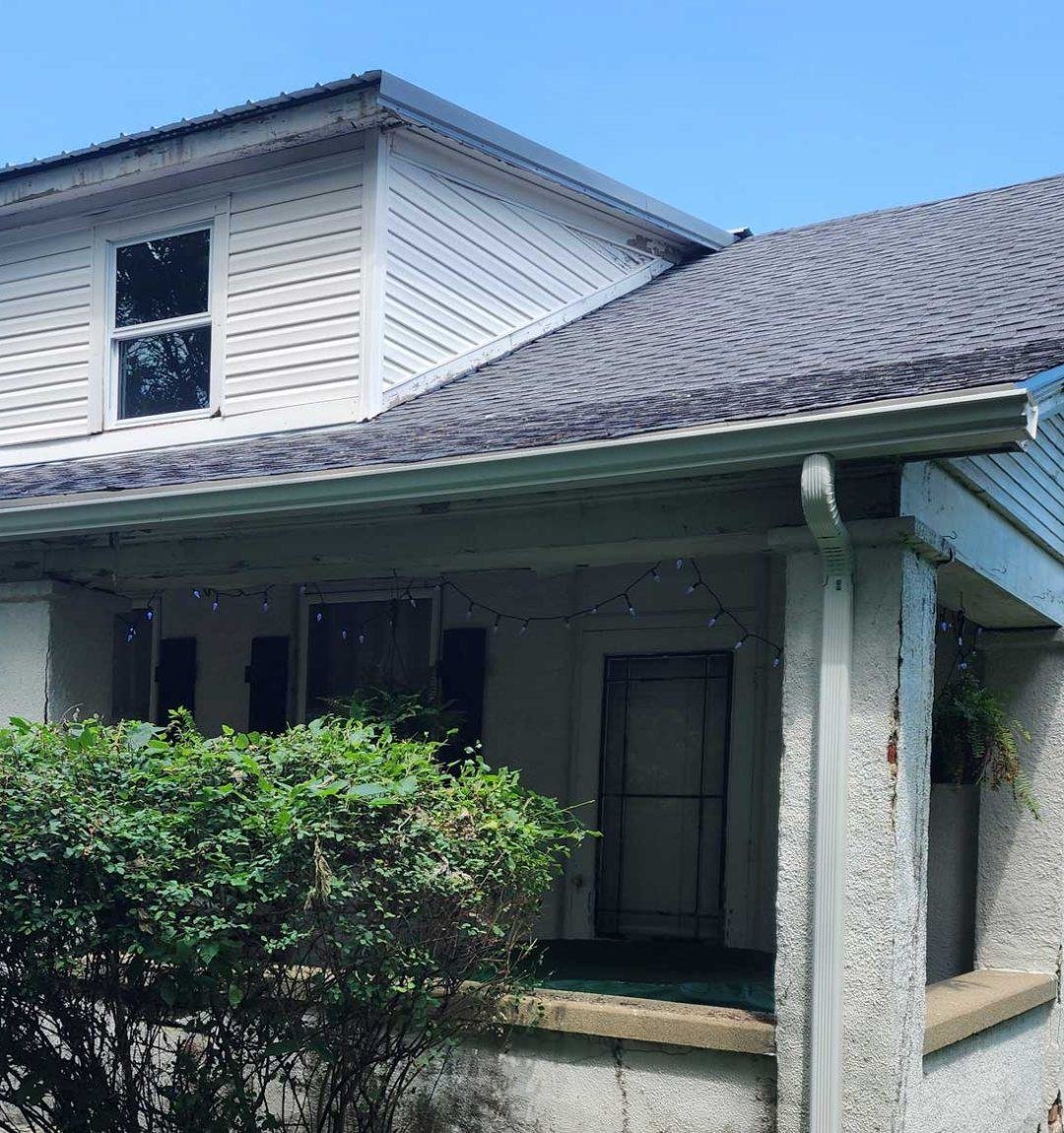 Home exterior with new white seamless gutters, downspout and vinyl siding dormer