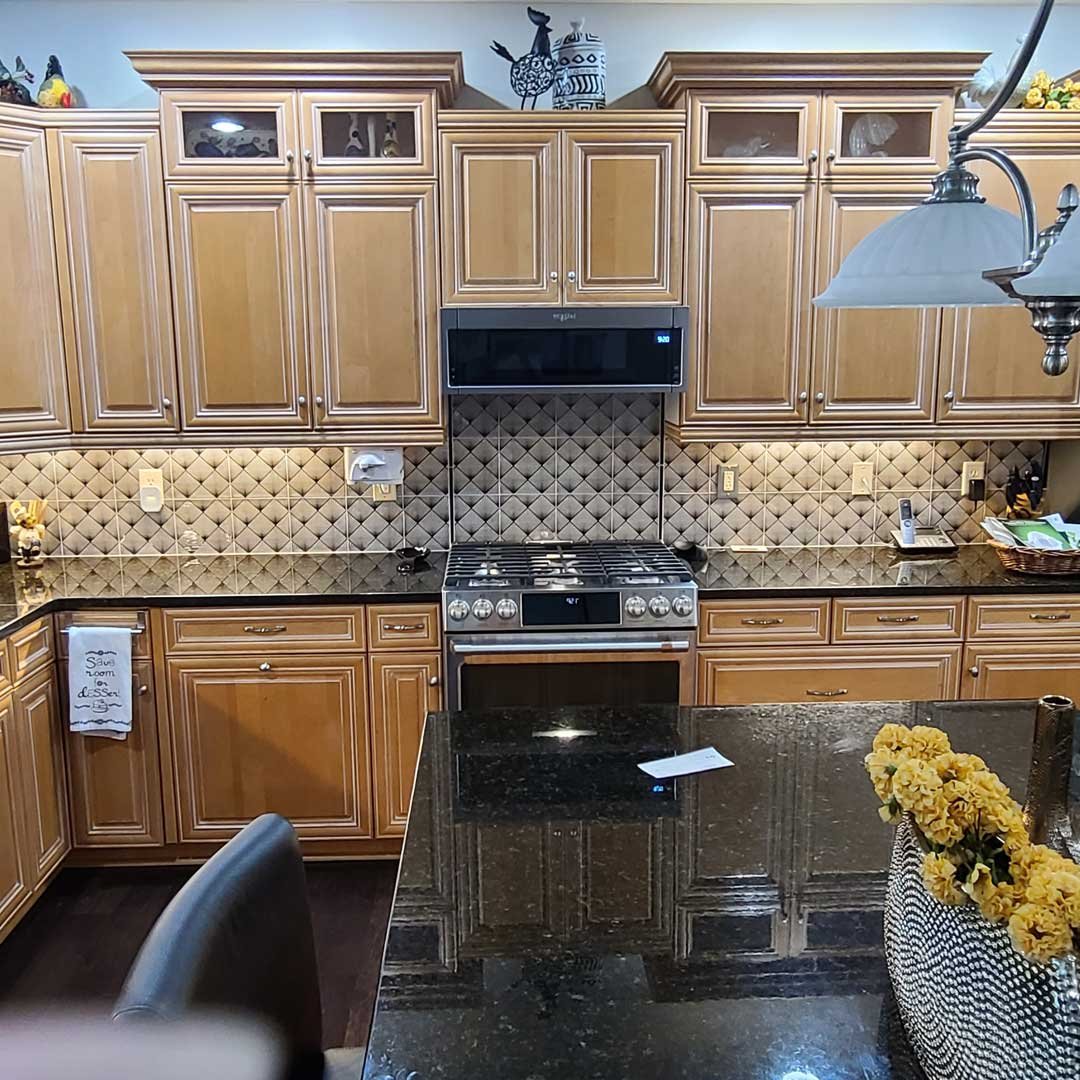 Kitchen with maple cabinets, black granite countertops and tile backsplash