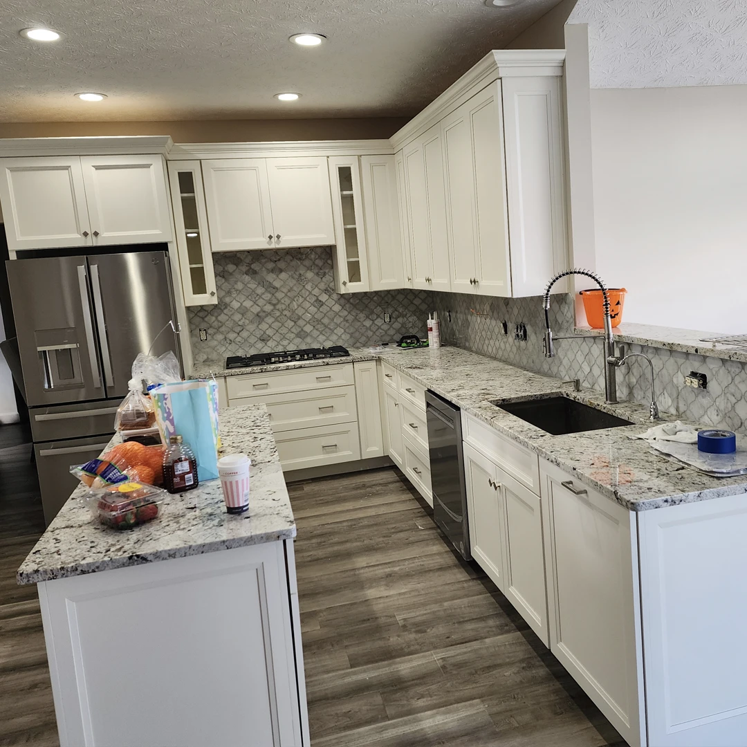 White shaker kitchen with granite countertops, subway tile backsplash and stainless appliances