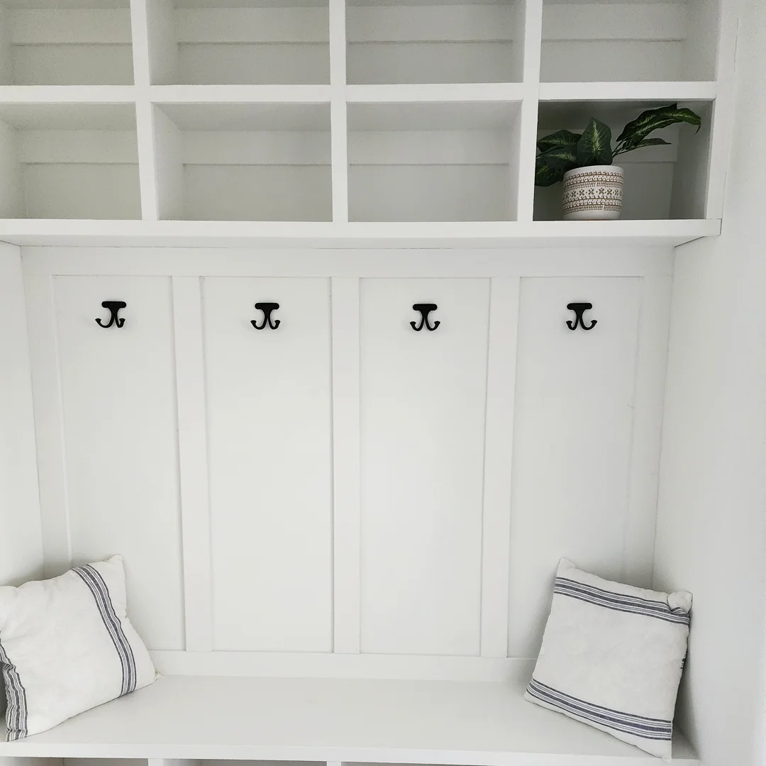White built-in mudroom bench with coat hooks and cubbies
