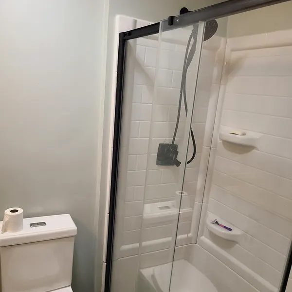Shower with white wall surround, corner shelves and sliding glass door