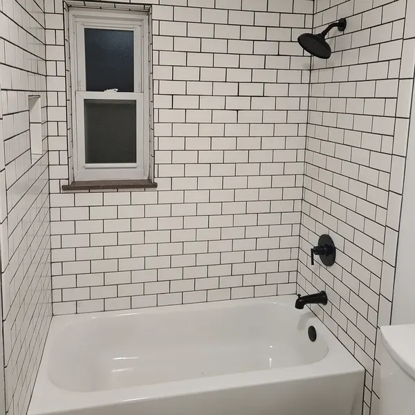 Bathtub with white subway tile surround and matte black fixtures