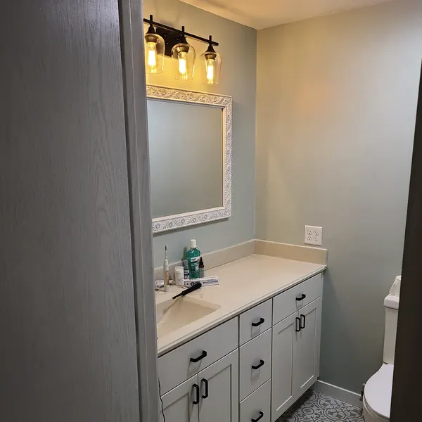 Bathroom with white shaker vanity and framed mirror