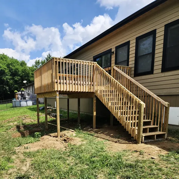 Raised pressure-treated deck with staircase on the side of a home