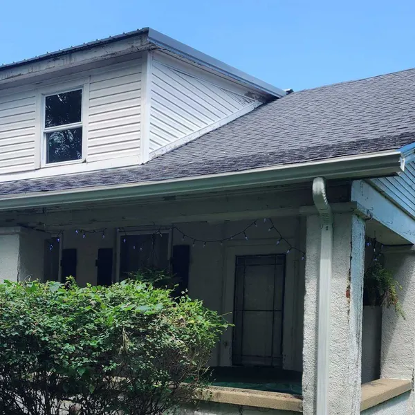 Home exterior with new white seamless gutters, downspout and vinyl siding dormer