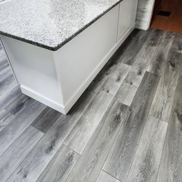 Gray luxury vinyl plank flooring beside a white kitchen island