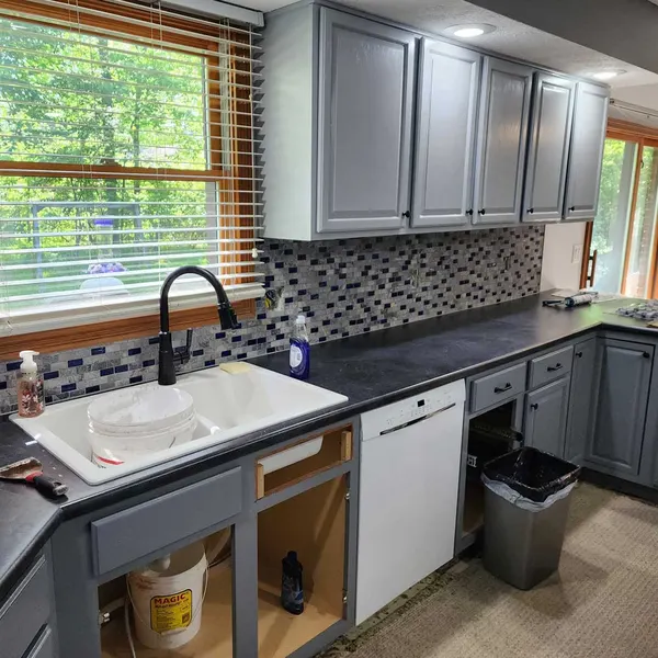 Kitchen with gray shaker cabinets, dark countertops, mosaic tile backsplash and white farmhouse sink