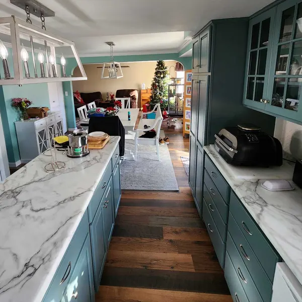 Galley kitchen with green cabinets, marble-look countertops and wood-look flooring