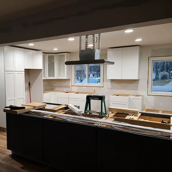 Kitchen remodel in progress with new white cabinets and a black island