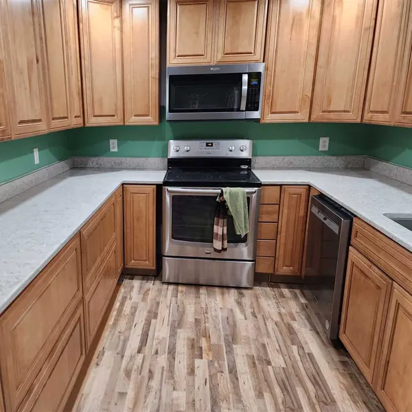 Kitchen with warm wood cabinets, light countertops and vinyl plank flooring