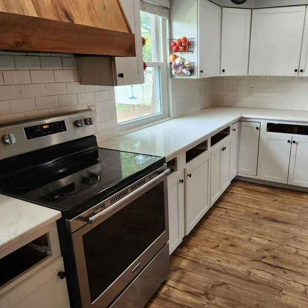 White kitchen with a wood range hood and white subway tile